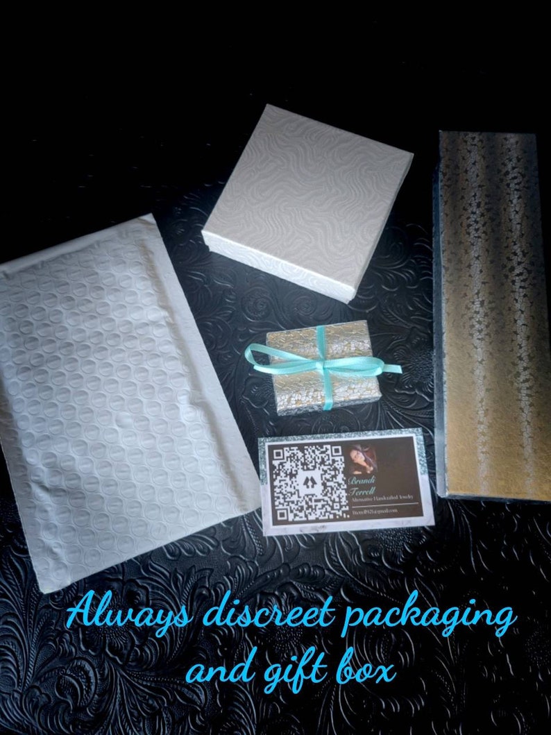 Puede incluir: Un sobre acolchado blanco, una caja de regalo blanca, una peque&ntilde;a caja de regalo plateada con una cinta turquesa, una caja de regalo dorada y una tarjeta de visita con un c&oacute;digo QR y el texto "Brandi Terrell" se muestran sobre una superficie texturizada negra. El texto "Siempre embalaje discreto y caja de regalo" est&aacute; escrito en azul sobre la superficie.