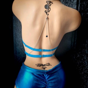 Puede incluir: Un conjunto de lencer&iacute;a azul con una cadena plateada y un dise&ntilde;o floral negro. El conjunto incluye un sujetador con tirantes ajustables y un par de pantalones cortos.