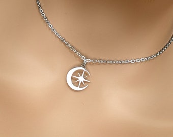 Puede incluir: Un collar de plata con un colgante de media luna con un diseño de estrella.