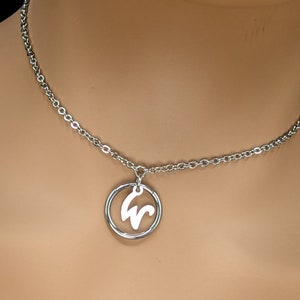 May include: A silver chain necklace with a circular pendant featuring a stylized letter 'W' cutout.
