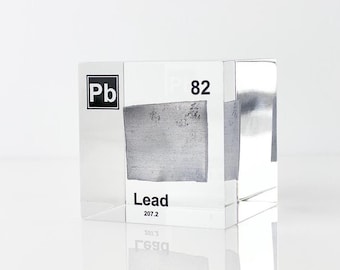 May include: A clear acrylic cube with a sample of lead inside. The cube has the chemical symbol "Pb" and atomic number "82" printed on it. The word "Lead" is also printed on the cube.