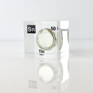 May include: A clear acrylic cube with a small sample of tin metal inside. The cube has the chemical symbol "Sn" and the atomic number "50" printed on it. The word "Tin" is also printed on the cube.