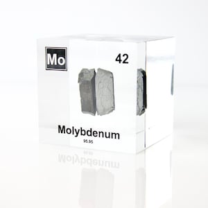 May include: A clear acrylic cube containing a sample of Molybdenum. The cube is labelled with the element symbol "Mo", atomic number "42", and the name "Molybdenum". The sample is a dark grey, irregularly shaped solid.