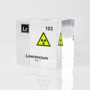 以下が含まれることがあります： 化学記号「Lr」と数字「103」が印刷された透明なアクリルキューブ。キューブには、「ローレンシウム」という言葉と原子量「[262]」も印刷されています。キューブには、黄色と黒の放射線警告記号が印刷されています。