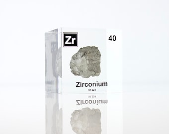 May include: A clear acrylic cube with a sample of Zirconium, a silvery-gray metal, inside. The cube also displays the element's symbol "Zr", atomic number "40", and atomic weight "91.224".