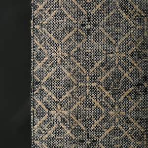 Puede incluir: Primer plano de una tela tejida con un patrón geométrico. El diseño presenta formas de diamante que se cruzan y motivos florales en beige sobre un fondo azul oscuro y blanco. La tela tiene una apariencia texturizada.