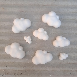 May include: A set of seven white cloud-shaped decorations. The clouds are made of a soft, lightweight material and are perfect for adding a touch of whimsy to any room.