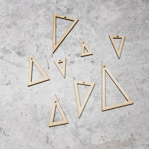 May include: A set of ten wooden triangle shapes with a hole in the top. The triangles are various sizes and are arranged on a grey concrete surface.