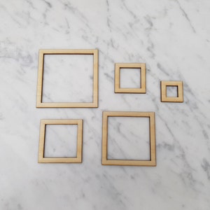 May include: Four wooden picture frames of different sizes, all with a natural wood finish. The frames are arranged on a white marble surface.