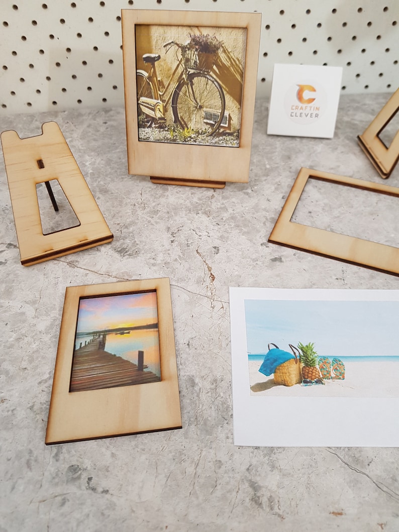 Peut inclure: Quatre cadres photo en bois avec un fond blanc et une vari&eacute;t&eacute; d'images. Les cadres sont tous de la m&ecirc;me taille et ont un design simple. Les images comprennent un v&eacute;lo, un coucher de soleil sur une jet&eacute;e, une sc&egrave;ne de plage et une carte blanche vierge avec le texte "Craftin Clever".