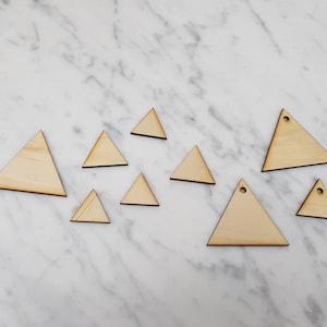 May include: A set of ten wooden triangle shapes in various sizes. The triangles are all made of light brown wood and have a smooth finish.