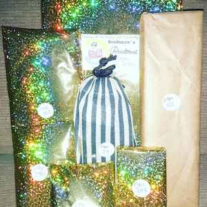 May include: Five gold glitter wrapped boxes with different page numbers on each. The boxes are arranged in a pyramid shape. The top box has a brown paper wrapper with the text "School of Witchcraft - Wizardry Bookworm's Readtreat Open the First Page".