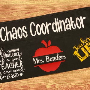 May include: Black teacher apron with white text that says "Chaos Coordinator" and "The influence of a good teacher can never be erased".  There is a red apple with the text "Mrs. Benders" and a yellow graphic that says "Teacher Life".