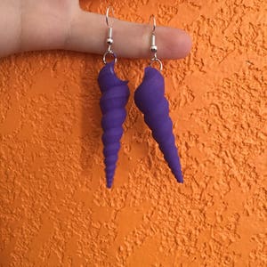May include: A pair of purple spiral shell earrings with silver hooks.