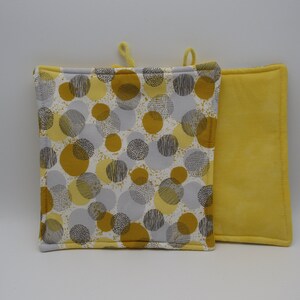 Peut inclure: Deux maniques de cuisine jaunes et grises avec un motif de cercles. Une manique est jaune unie et l'autre a un fond blanc avec des cercles gris et jaunes.