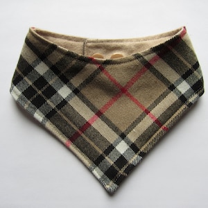 May include: A brown, black, white and red plaid bandana with a brown fabric lining. The bandana has two small, round, beige buttons.