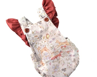 Op de afbeelding: Een witte en bruine baby romper met een bosdierprint. De romper heeft rode stof banden met ruches.