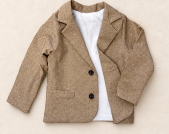 Pode incluir: Um blazer bege com acabamento texturizado, apresentando lapelas entalhadas, mangas compridas e dois botões escuros na frente. O casaco é sobreposto a uma camisa branca lisa, criando um visual estruturado com costuras e bolsos visíveis.