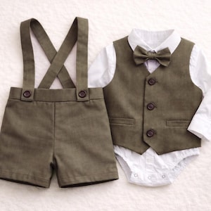 May include: Olive green suspender shorts set with a matching vest, bow tie, and white collared bodysuit. The vest has three buttons. This formal outfit is perfect for a baby boy's special occasion.