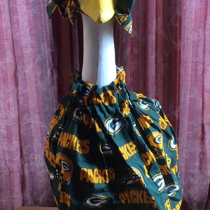May include: A white goose figurine wearing a green and gold fabric hat and skirt with the words "Packers" printed on it.