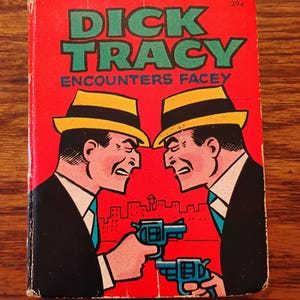 May include: Vintage comic book cover for "Dick Tracy Encounters Facey." The cover features two men in suits and fedoras pointing blue revolvers at each other. The title is in green block letters on a red background. The price is 39¢.