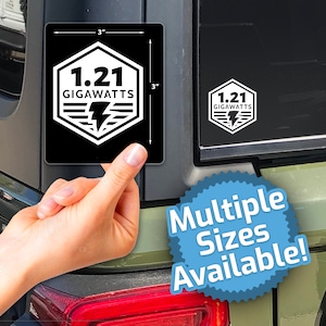 May include: A black and white sticker with the text "1.21 GIGAWATTS" and a lightning bolt inside a hexagon. The sticker is 3 inches by 3 inches and is shown on a green car.