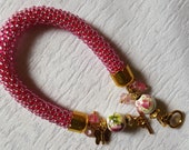 Pink Beaded Bracelet with porcelain, glass beads, and a small butterfly pendant. Beaded crochet rope