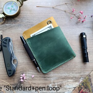 May include: A green leather wallet with a yellow leather flap and a pen loop. The wallet is closed and has a stitching detail around the edges. The text "size "Standard + pen loop"" is visible at the bottom of the image.