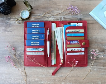 May include: Red leather travel wallet with multiple slots for credit cards, cash, and passports. The wallet is open and shows a stack of Ukrainian passports, cash, and credit cards.