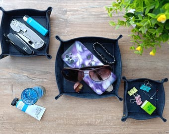 May include: Three blue suede catchall trays with various items inside, including a multi-tool, a lighter, a phone case, sunglasses, a bracelet, and a few small items.
