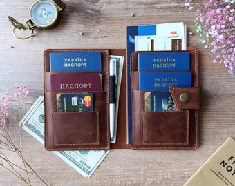 May include: A brown leather passport holder with multiple pockets and slots for cards, cash, and passports. The holder has a snap closure and is embossed with the text "UKRAINE PASSPORT".