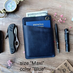 May include: A blue leather wallet with a pocket for a passport. The wallet is labeled "Maxi" and "Blue".