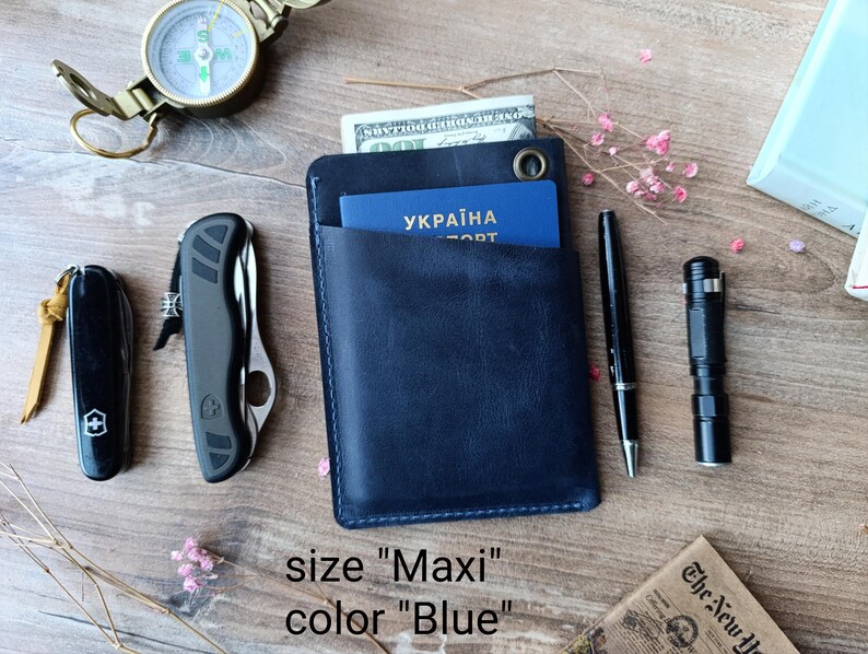 May include: A blue leather wallet with a pocket for a passport. The wallet is labeled "Maxi" and "Blue".