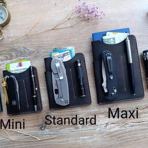 May include: Three leather wallet styles, labeled "Mini", "Standard", and "Maxi", with different sized pockets for carrying cash, cards, and small tools. Each wallet has a brown leather exterior with contrasting stitching.
