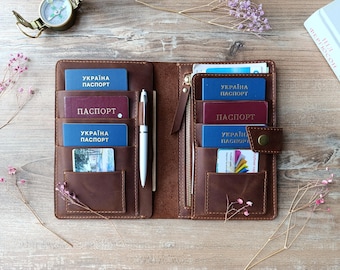 May include: A brown leather passport holder with multiple pockets and slots for holding passports, cards, and a pen. The holder is open and shows the interior with several passports inside, including two blue passports with the text "Україна паспорт" and two burgundy passports with the text "ПАСПОРТ".