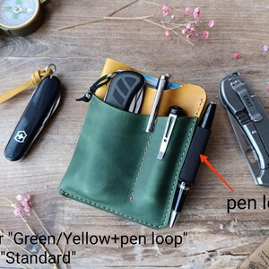 May include: A green leather wallet with a yellow interior and a pen loop. The wallet has two slots for carrying pens or other small items. The text "color "Green/Yellow+pen loop" and "size "Standard" is visible below the wallet.