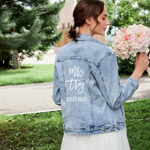 May include: A light blue denim jacket with white text on the back that says "mrs. troy 09.22.2021".