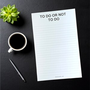 May include: A white notepad with the text "To Do Or Not To Do" at the top. The notepad has lined paper and a website address at the bottom. The notepad is on a black surface with a cup of coffee and a succulent plant.