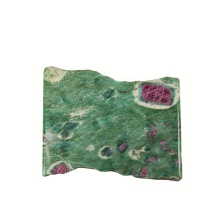 May include: A rectangular slab of polished green zoisite stone featuring embedded magenta-colored ruby crystals. The surface displays a mottled texture with varying shades of forest green, white, and dark green, accented by distinct, angular ruby inclusions.