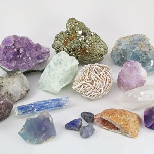 May include: A collection of various crystals and minerals, including amethyst, pyrite, celestite, and desert rose. The gemstones display a range of colors, from purple and blue to gold and white. The arrangement showcases the natural beauty and diversity of these geological specimens.