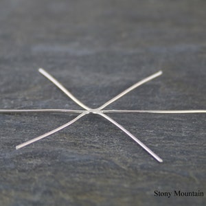 May include: A silver six-prong bezel setting for a gemstone. The prongs are straight and evenly spaced.