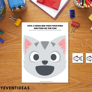 May include: A printable game for kids featuring a gray cat with a big smile and two fish cards with the numbers 1 and 6. The text on the page reads "Pick 2 cards add them together and feed me the fish".