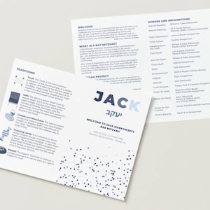 May include: A folded white paper programme for a Bar Mitzvah featuring blue text and graphics. The front displays the name JACK in large blue letters, event details, and a confetti pattern. The interior contains sections on traditions and honours.