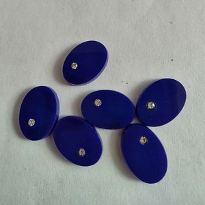 May include: Six oval-shaped blue buttons with a single rhinestone in the center of each button.