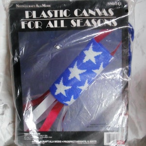 May include: A plastic canvas kit for needlepoint projects. The kit includes a blue and white canvas with a star pattern, red and white ribbon, and instructions. The packaging says "Plastic Canvas for All Seasons" and "Needlecraft Ala Mode".