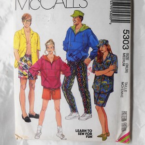 May include: A sewing pattern for three different outfits. The pattern is for a medium size and is called McCall's 5303. The outfits include a blue jacket with a zipper, a red jacket with a zipper, and a blue and white patterned shirt. The pattern is on a white background with a pink, green, and yellow stripe on the right side.