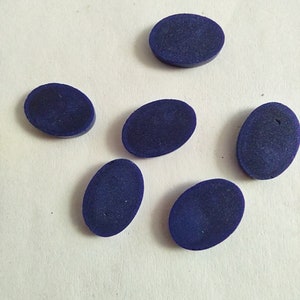 May include: Six oval-shaped, dark blue gemstones. The gemstones are smooth and polished.