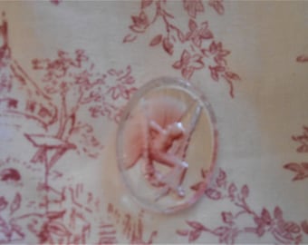 May include: A clear glass cameo with a pink, raised design of a woman holding a flower. The cameo is set in a silver tone frame.