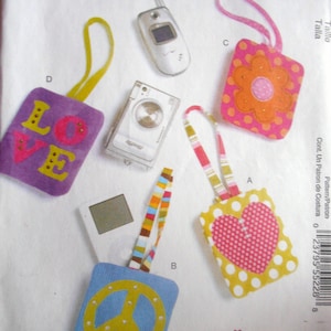May include: A set of five DIY craft projects for making keychains. The projects include a peace sign, a heart, a flower, a camera, and a word "LOVE" keychain. The keychains are made from felt and fabric and are decorated with rhinestones.