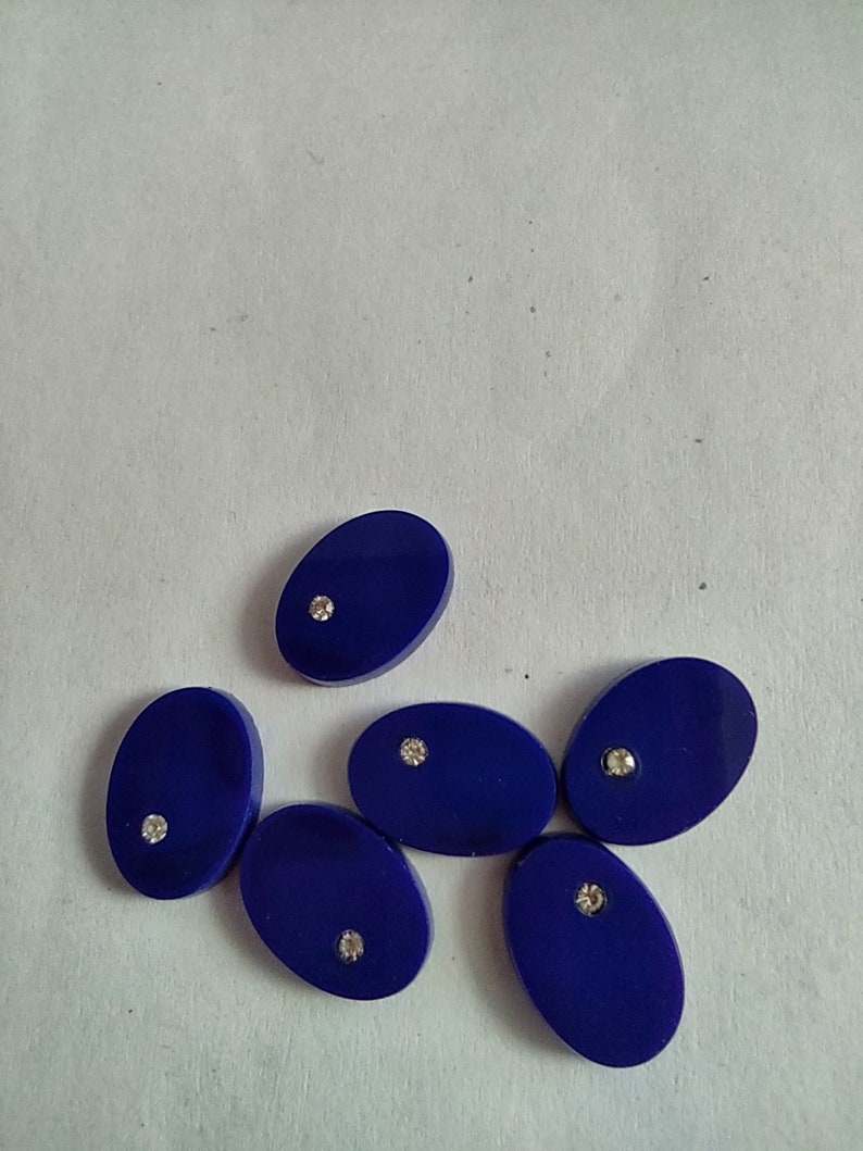 May include: Six oval-shaped blue buttons with a single rhinestone in the center of each button.